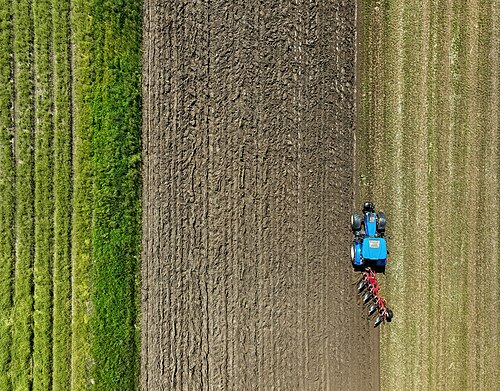 A tractor ploughing a field, seen from above