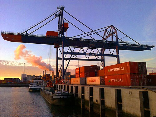Container cranes loading a ship in a port at sunset